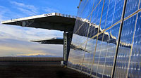 Photo of flat solar panel, angled vertically, that reflecst the solar panels nearby that are angled horizontally.