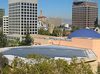 Photo of an urban roof covered in solar photovoltaic panels; city skyscrapers fill the background.