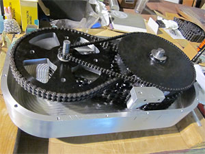 Photo of a machine with two round discs connected by intertwined chains.