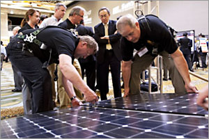 Photo of a group of men moving a rectangular solar panel.