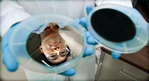 Photo of a researcher holding two disc-shaped solar cells, one that is black and one that is reflective, showing his face.