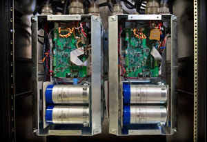 Photo of two inverters with covers removed, showing switches, circuits, a digital controller board, bussing and connectors.