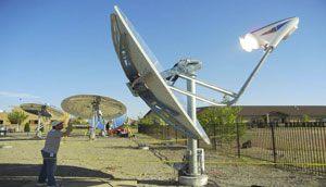 Photo of large silver dish angled to the sky and anchored to the ground.