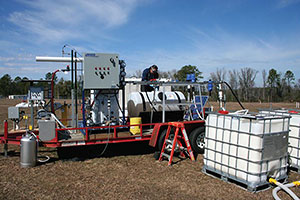 Image of a man working ona trailer with technical equipment outside in a field.