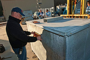 Image of a man putting a numbered decal on a large metal container.