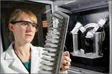 Researcher loads a sample mount of battery cathode materials for X-ray diffraction, an analysis tool for obtaining information on the crystallographic structure and composition of materials.
