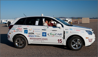 Photo of the Mississippi State University winning vehicle from year two of the EcoCAR competition. The sport utility vehicle is white with many decals on the body of the vehicle including the team name, Mississippi State University. The background is the GM's Desert Proving Grounds in Yuma, Arizona.
