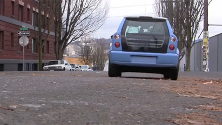 a blue plug-in electric vehicle driving down a city street