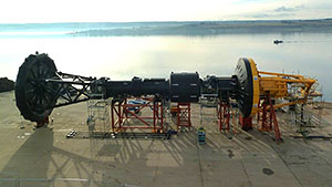 The OPT Power Buoy set up on the shore. The device has a buoy on one side and a turbine on the other.