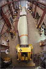 Photo of a long, white, curved wind turbine blade in a high-bay test facility.