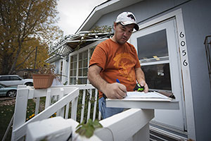 Photo of a weatherization worker writing notes for an energy audit on a clipboard.