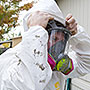 Photo of a weatherization worker putting on personal protective equipment to prepare for adding insulation to this home.