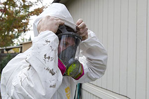 Photo of a weatherization worker putting on personal protective equipment to prepare for adding insulation to this home.