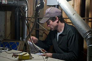 Photo of a weatherization worker conducting a furnace safety check.