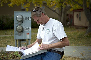 Photo of a weatherization worker reviewing notes conducted during an energy audit on a clipboard.