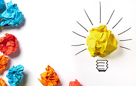 Image of crumpled-up colored paper, forming the shape of a light bulb.