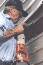 Photo of worker cutting into the siding of a house with a reciprocating saw.