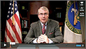 Photo of Matt Rogers, senior advisor to Energy Secretary Steven Chu, seated at a desk that has a U.S. flag on his right hand and a flag with the U.S. Department of Energy insignia on is left-hand side.