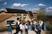 Photo of people walking toward a one-story home with a solar PV system on the roof.