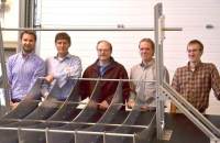 Five men standing behind the metal frame of a CSP receiver.